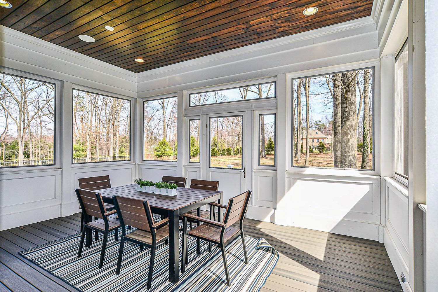 screened porch converted into a sunroom white walls wood ceiling brown decking simple decor