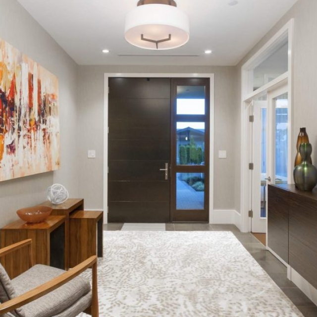 contemporary home builder - entry with modern dark wood front door, single sidelight, gray tiles with light patterned area rug
