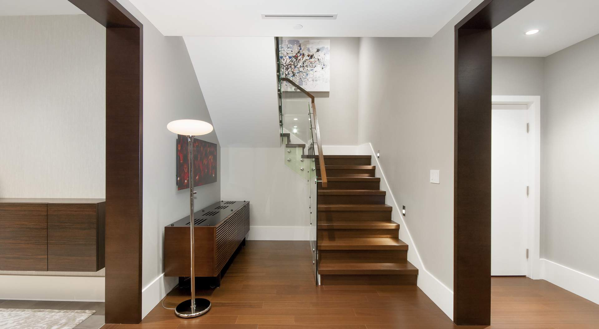 modern wood stairs with glass railings, wood floors and door trim, large white base trim