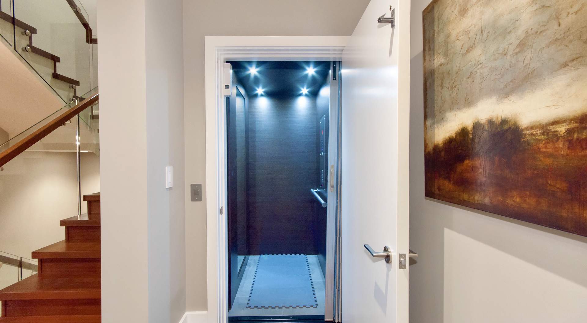 Contemporary home elevator, white door with brushed hardware, brown wood walls with tile floor, LED lighting