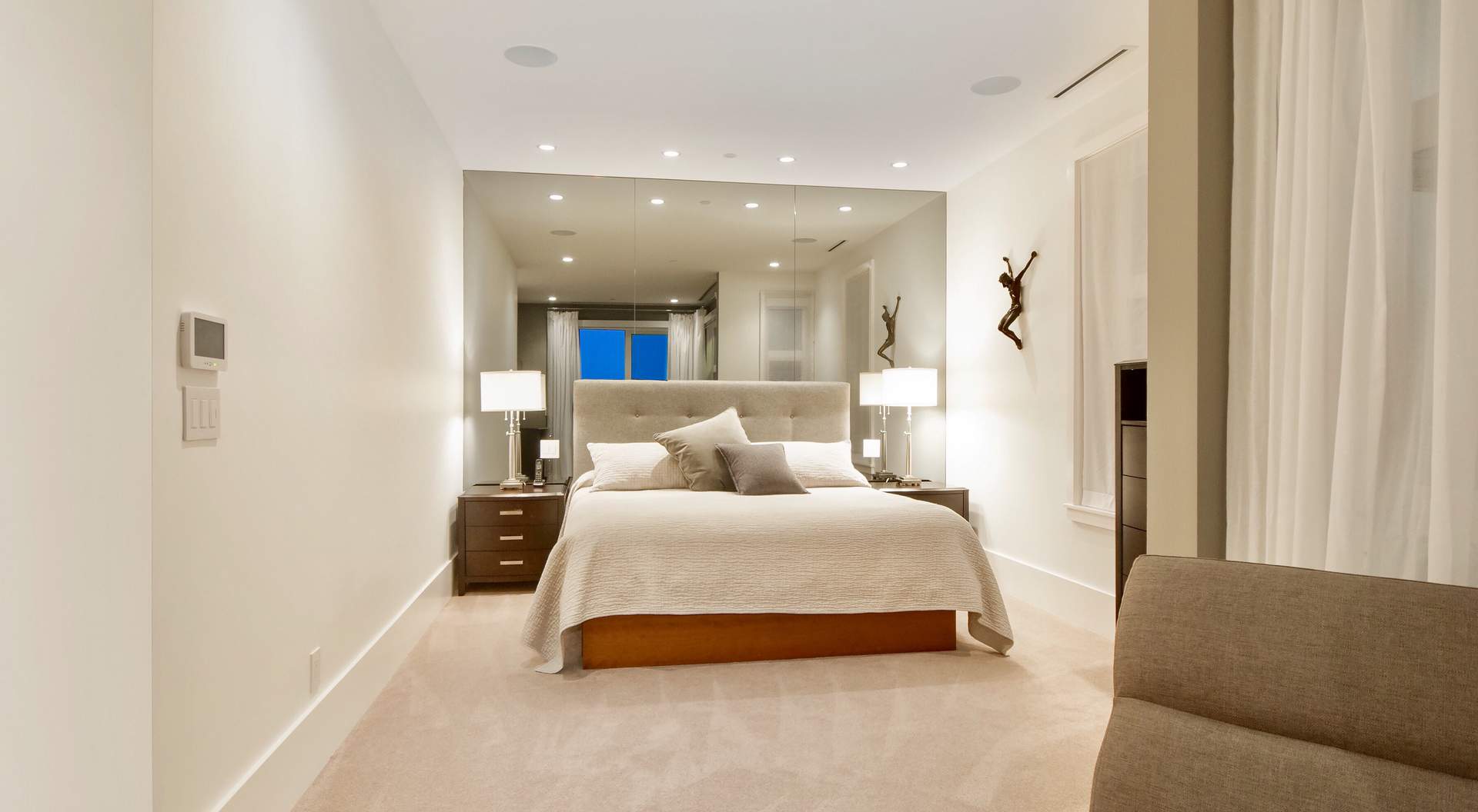 Contemporary bedroom design, tan rugs with white walls, ceilings and trim, huge wall mirror, LED lighting