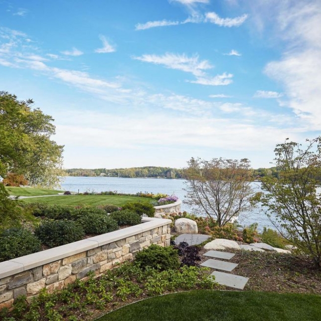 waterfront real stone retaining wall with concrete cap and beautiful landscaping