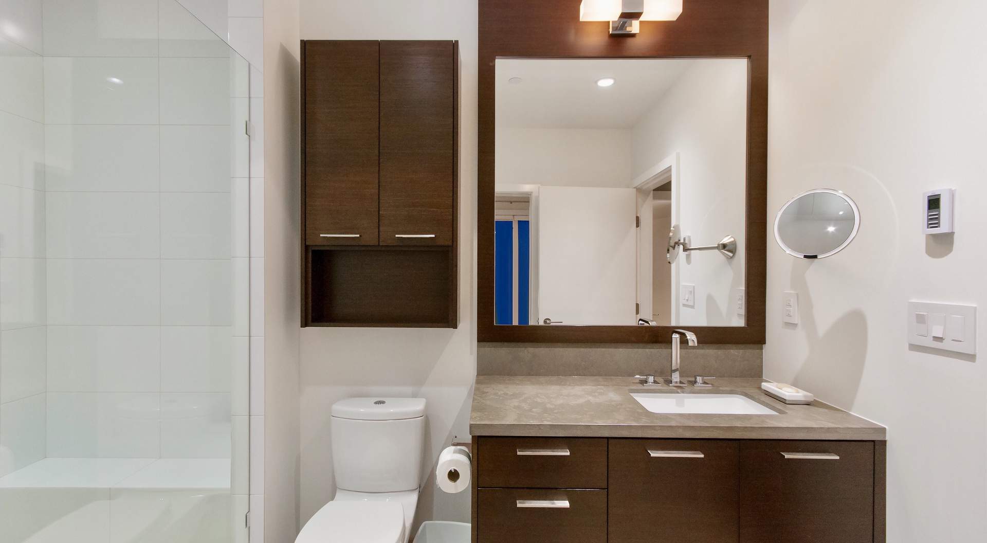 modern bathroom, dark wood vanity, large mirror with wood frame, chrome fixtures,