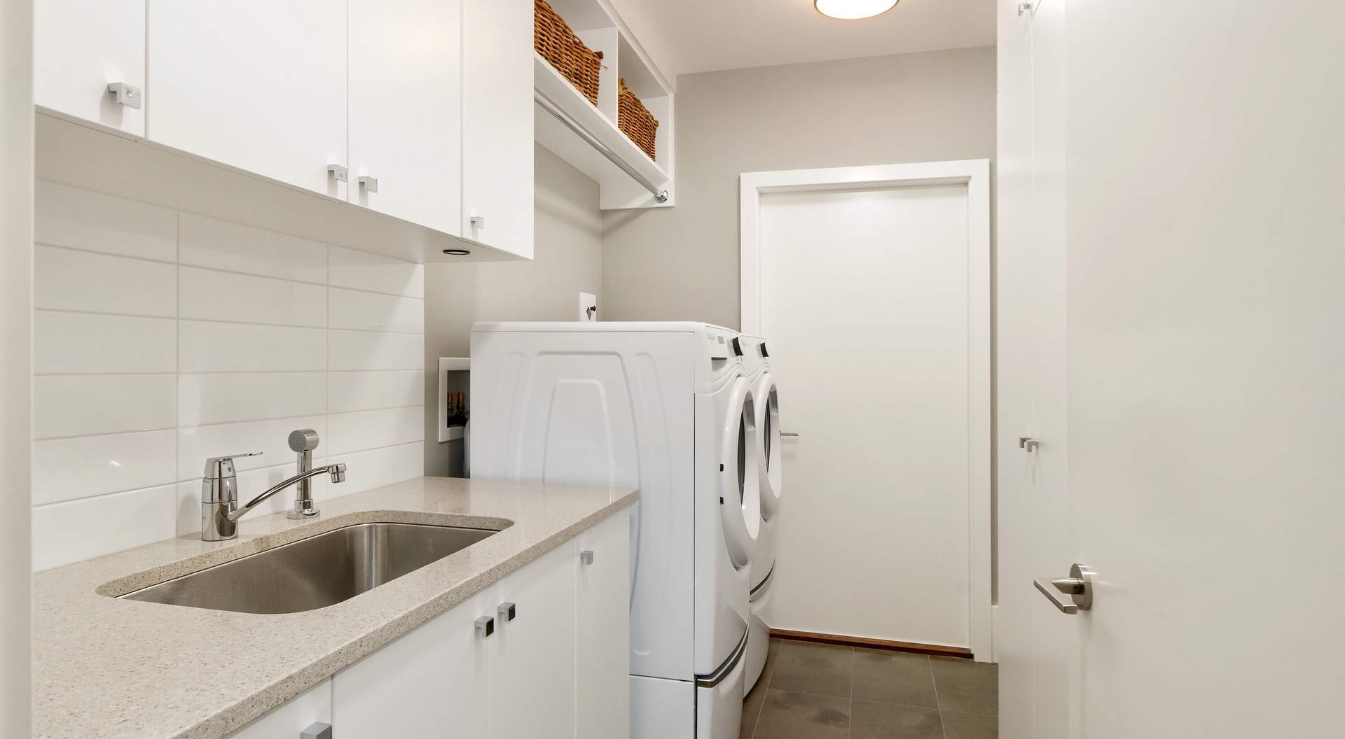 laundry room with white cabinets and white porcelain tile backsplash, white washer  dryer