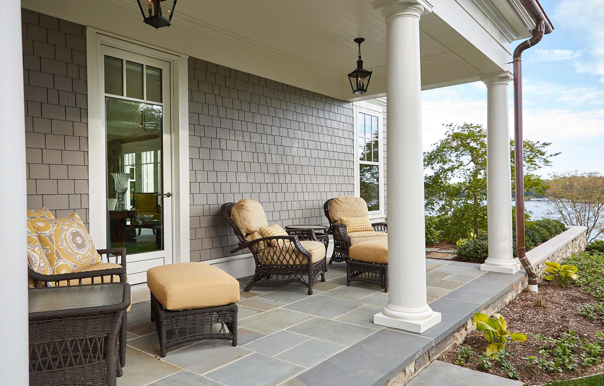 covered porch water views bluestone patio round columns gray siding with white azek copper gutters