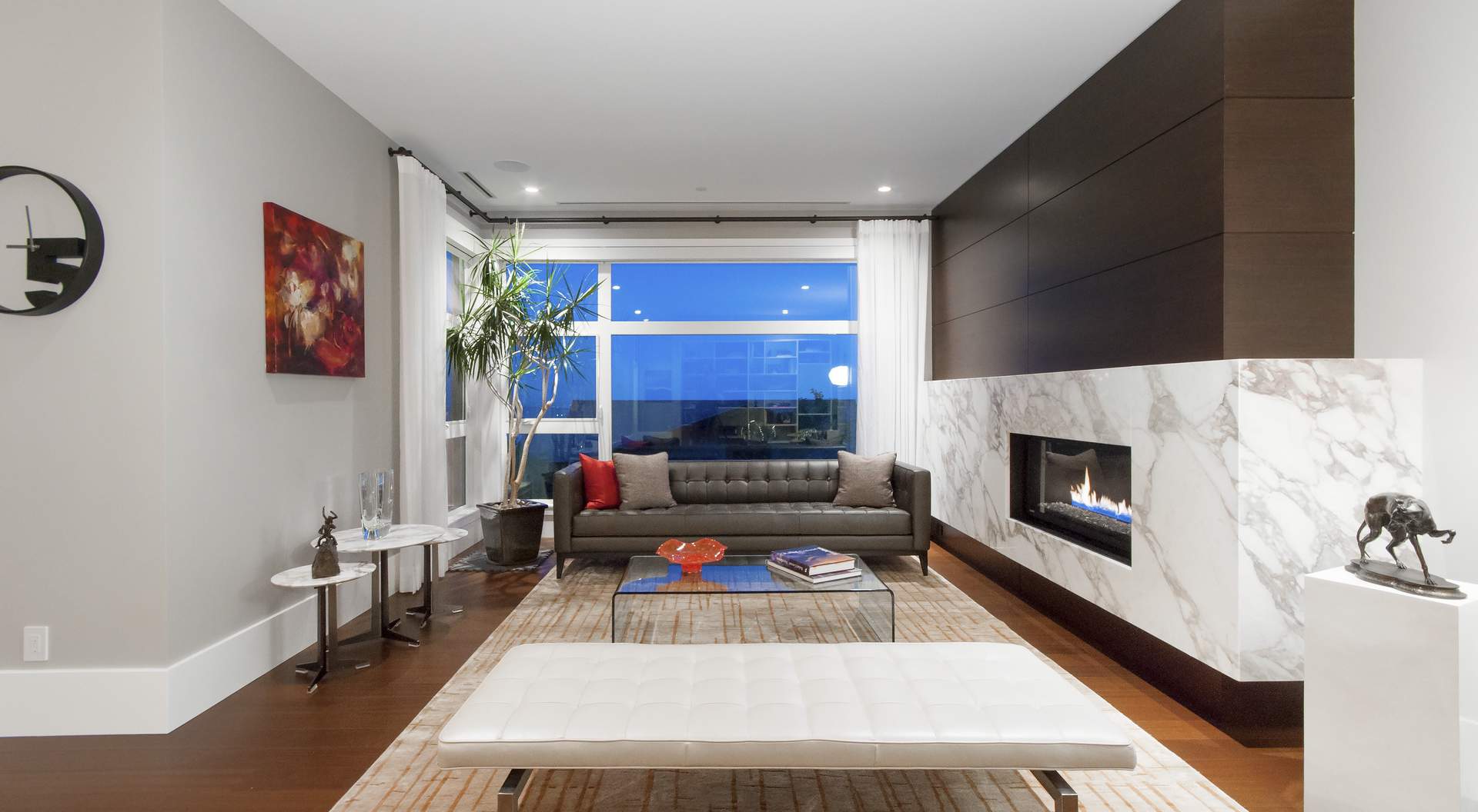 Modern living room, medium dark wood floors, modern fireplace with huge marble surround, gray walls
