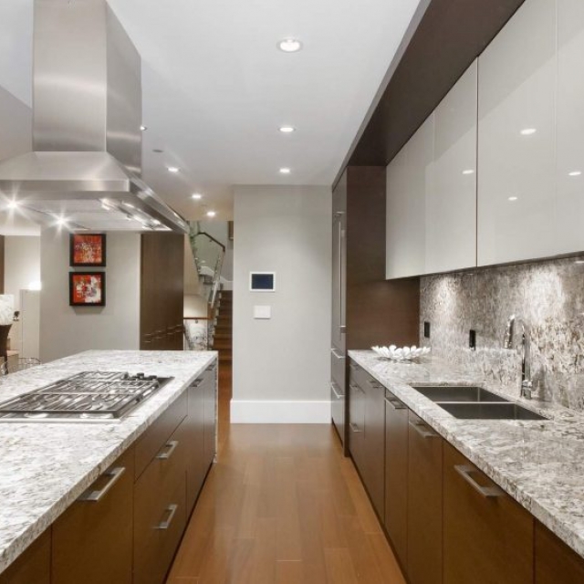 Modern home builder - kitchen - matching stone counters and backsplash, stainless steel, medium wood and white cabinets