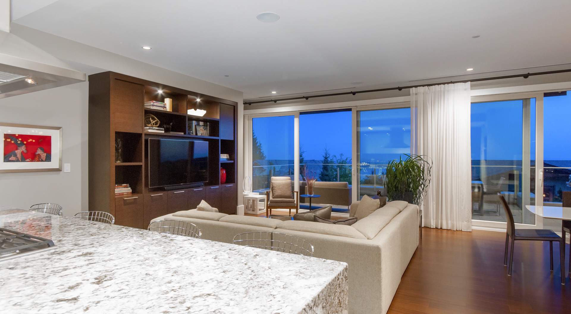 modern home builder - glass walls with water views, plush tan sofa, wood built ins