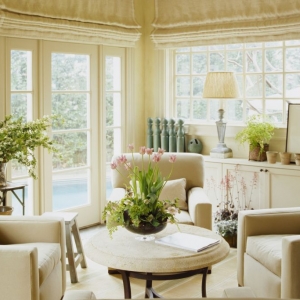 cream colored sunroom with roll down drapes built in cabinets cream plush chairs