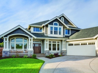 Two toned light and dark gray siding colors with white trim and columns with white railings. White garage doors. Dark brown stained front door. Light brown stone veneer.