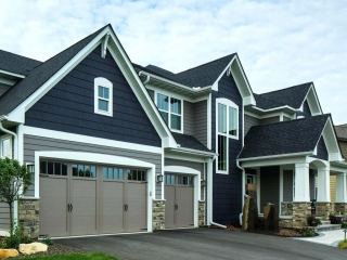 Two toned blueand gray siding color combination. Black roofing shingle. Taupe garage doors. Brown stone veneer. White trim and columns.