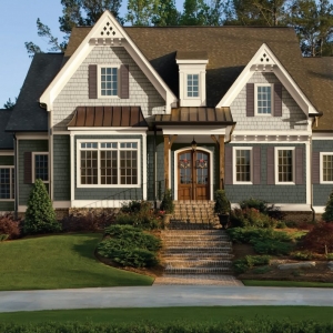 Two toned white and blue gray siding colors scheme with black roofing shingles and black metal accents. Real wood columns. White trim. Stained brown real wood front door. Red brick veneer and steps.