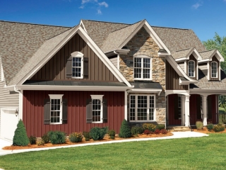 Red and brown two toned vertical siding colors with brown roofing shingles and black metal accents. White trim and columns with black metal railings. Brown stone veneer.