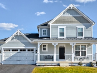 Blue, gray and white siding color scheme. White trim and columns. Black metal accent roof. Black shingled roof. Vertical siding accents. White garage door with black front door.