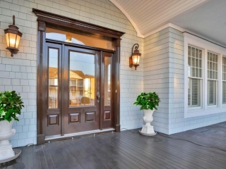 Front porch with light gray cedar shake siding, dark brown stained wood front door, white trim and soffit with recessed lighting. Dark brown stained wood front porch.