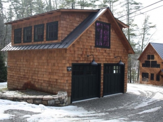 Detached garage design with cedar shake wood siding and black trim. Black garage doors. Black metal roofing.
