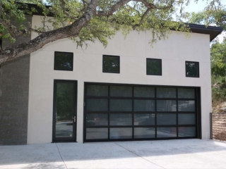 Two car detached garage with a modern design. White stucco finish and concrete block. Black framed windows and doors. Black trim. Concrete driveway..