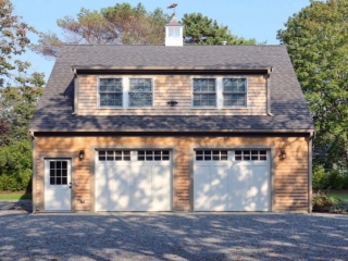 Two car garage design with second floor living space. White doors with gray trim. Real wood cedar shake siding.