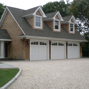 Three car detached garage design. White doors with real wood cedar shake siding. White columns and trim. 2nd Floor living space.
