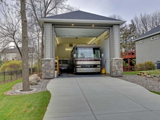 One car oversized garage design. Big enough to fit a bus. Gray cedar shake siding with dark gray trim. Real stone veneer.