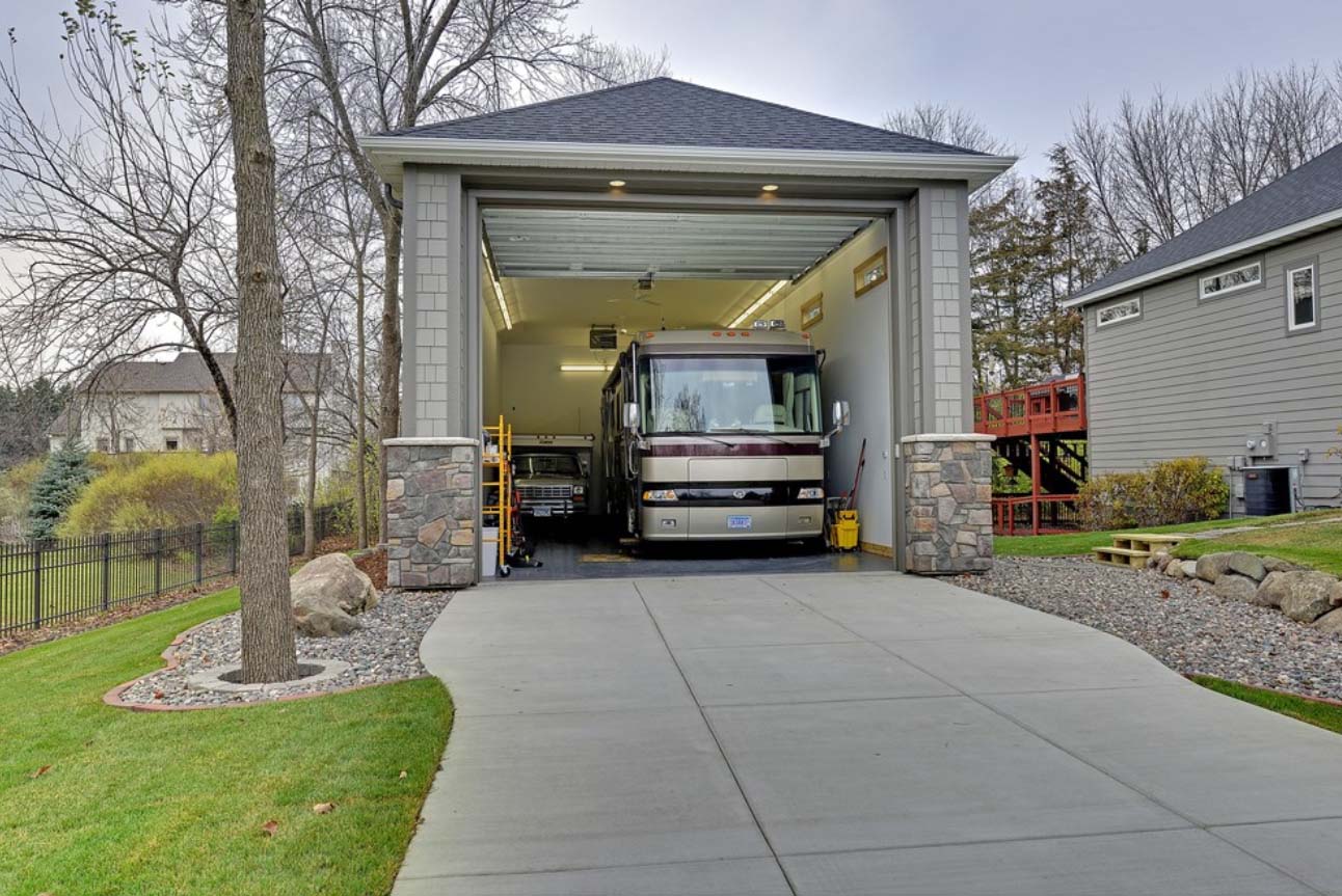 One car oversized garage design. Big enough to fit a bus. Gray cedar shake siding with dark gray trim. Real stone veneer.