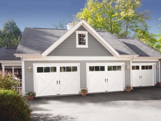Three car detached garage design with porch. Gray siding with white trim and white garage doors.