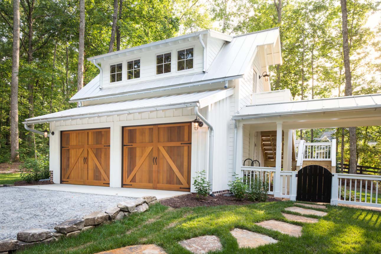 detached garage with white vertical siding wood doors and metal roof with shed dormer