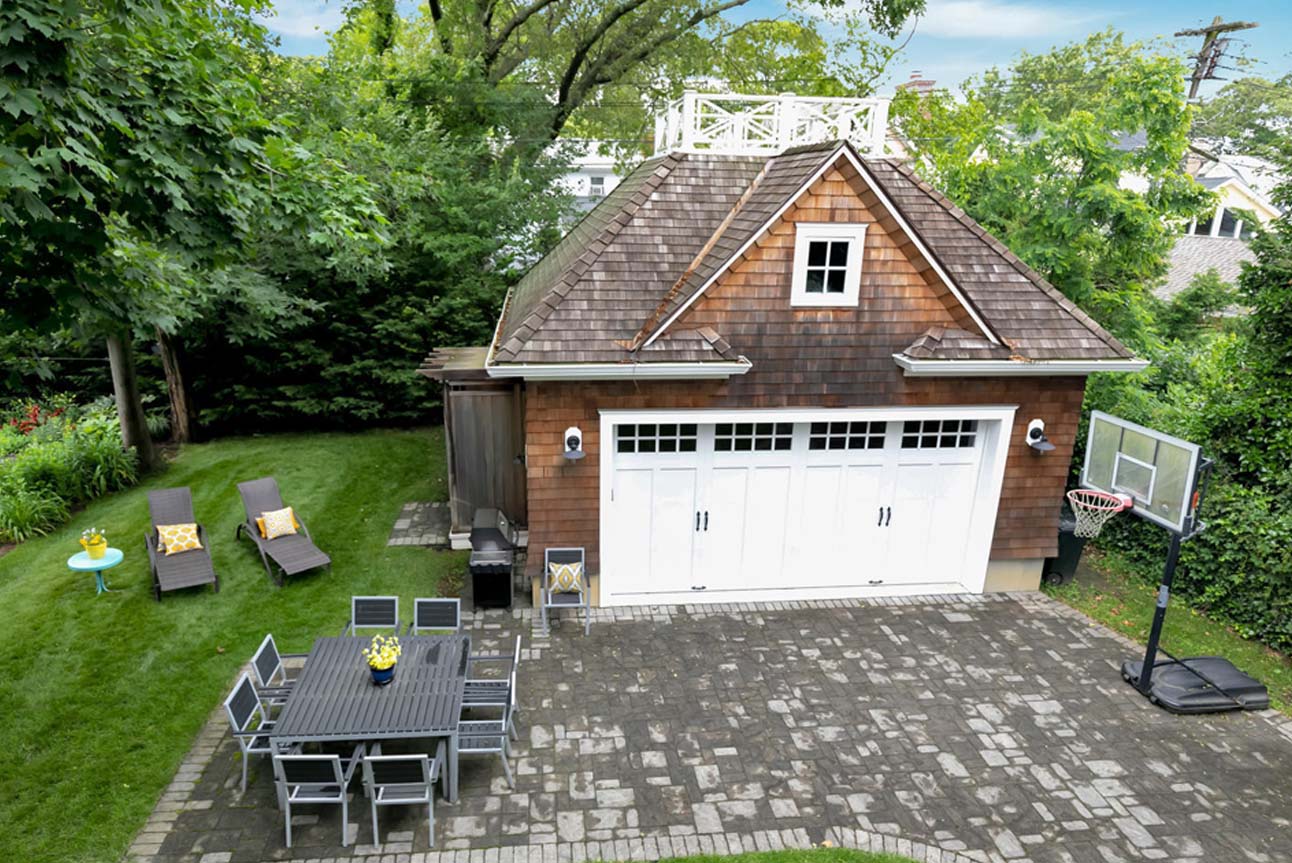 Small single car detached garage with roof top deck and outdoor shower. Real wood cedar shake siding with white garage door.