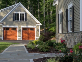 beautiful detached garage with white trim wood doors and lap siding black shutters and dormer