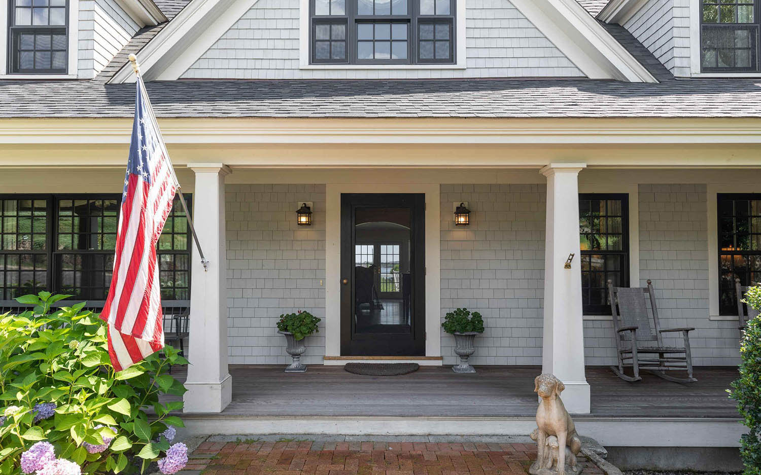 Gray house siding colors with black front door and white trim. White columns. Black framedwindows.