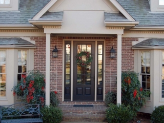 black front door with side transoms tan trim with red brick house