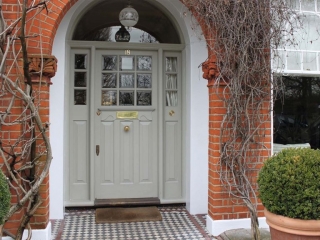 Light gray front door with transoms white trim and red brick house green porch plants vines