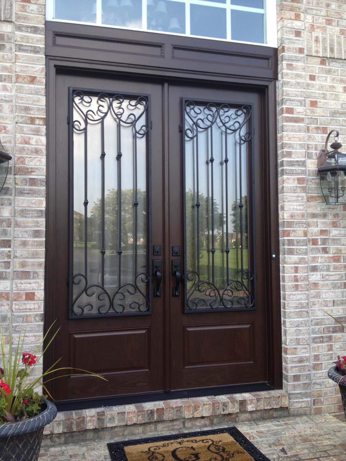 dark brown front french door with glass transom windows black iron scroll work with red brick house