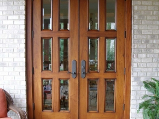 natural wood french style front door with glass on a brick house