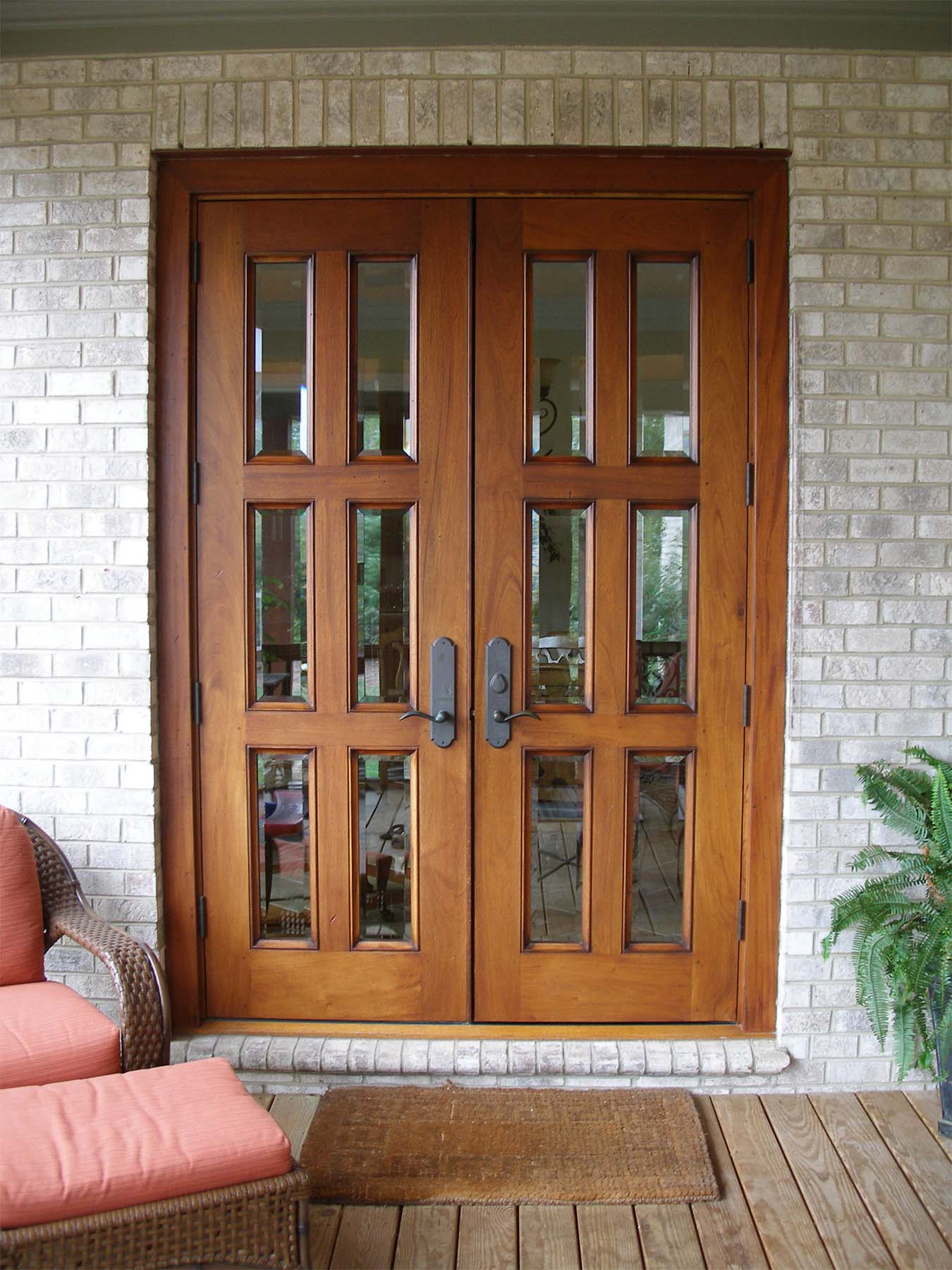 natural wood french style front door with glass on a brick house