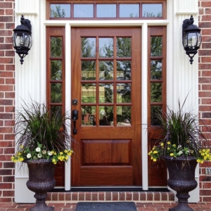 natural wood stained front door with transoms white trim on a red brick house beautiful porch plants