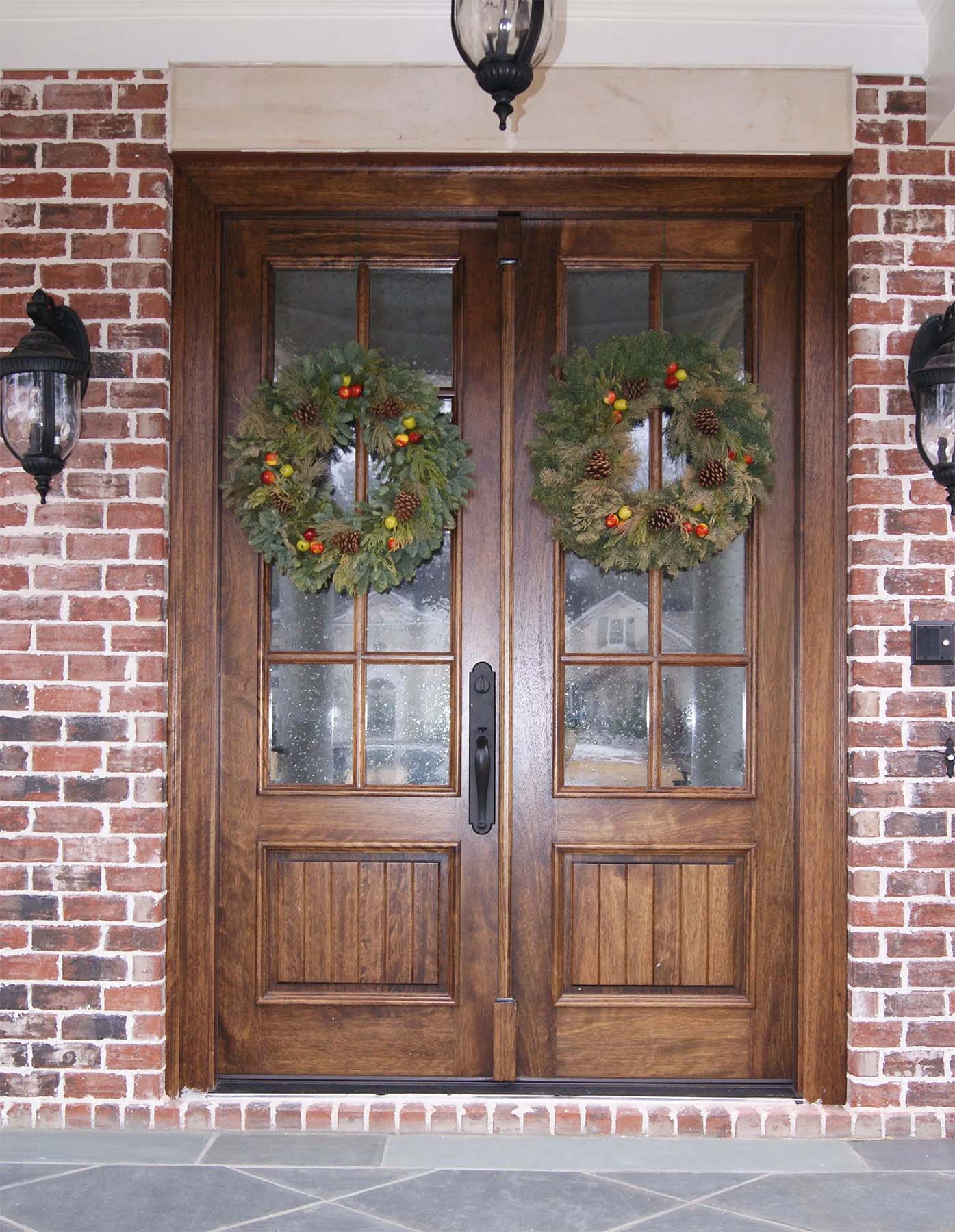 natural wood french front door with glass on a red brick house