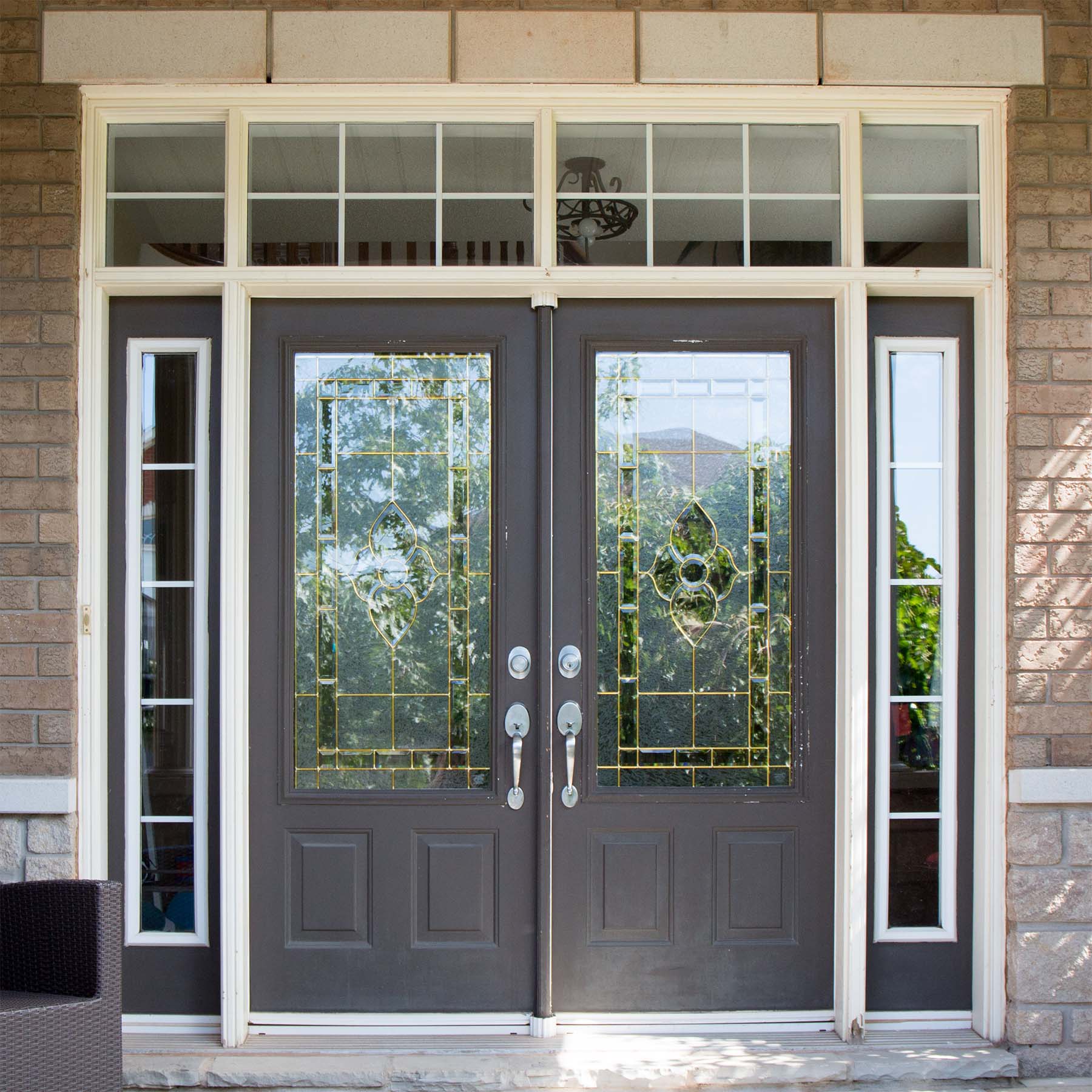 dark gray french style front door with glass transoms on a brick house