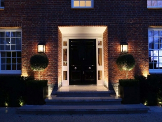 black front door with glass transoms and white trim beautiful landscaping brick house at night