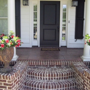 black front door with glass transoms white house with black shutters red brick front steps