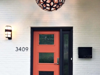 modern style orange front door with black trim and single transom on white brick house