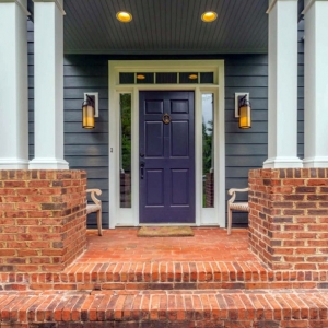 purple front door with glass transoms white trim blue siding with red brick columns front steps