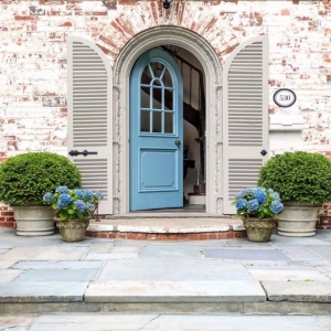 light blue front door with white washed red brick house blue stone patio and porch plants