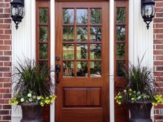 beautiful Natural wood front door with glass transoms white trim red brick house colorful porch plants