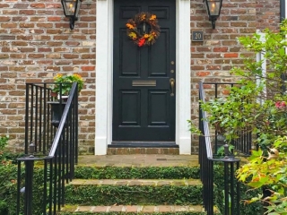beautiful black front door on a red brick house white trim black iron railings lots of plants