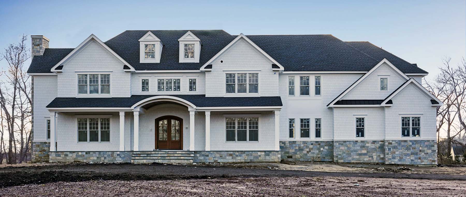 stunning custom home white siding real stone base brown front door