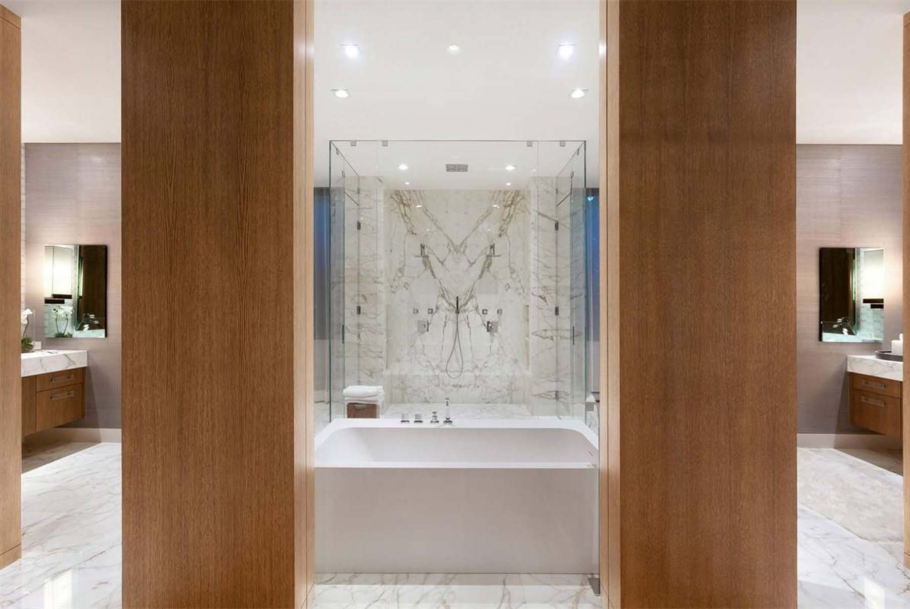Beautiful master bathroom with marble and real wood. center soaking tub and glass shower.