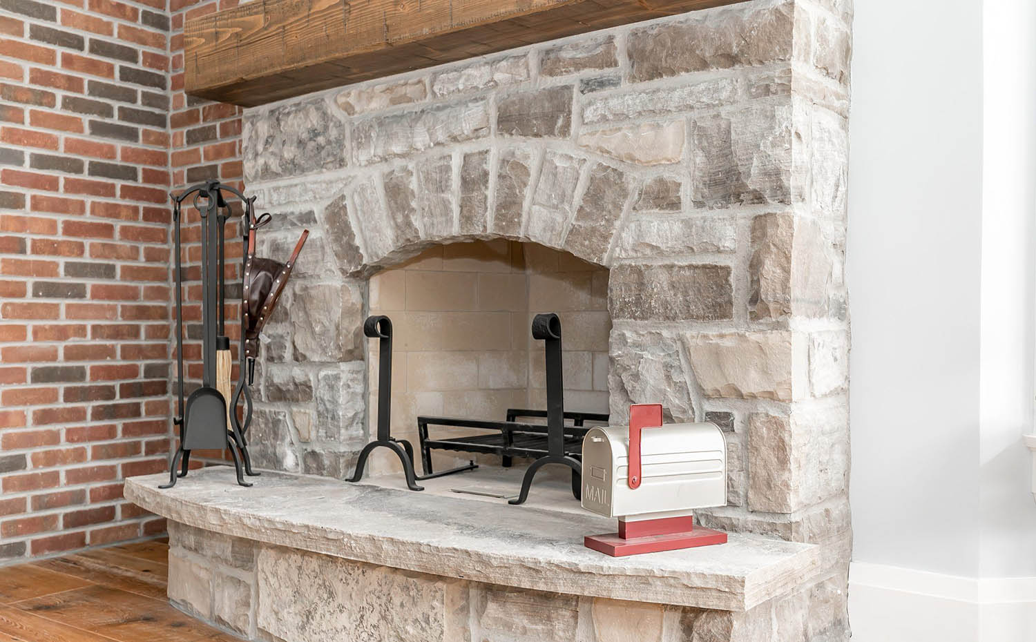 Light gray wall paint with red brick walls and a stone fireplace with wood mantle closeup picture
