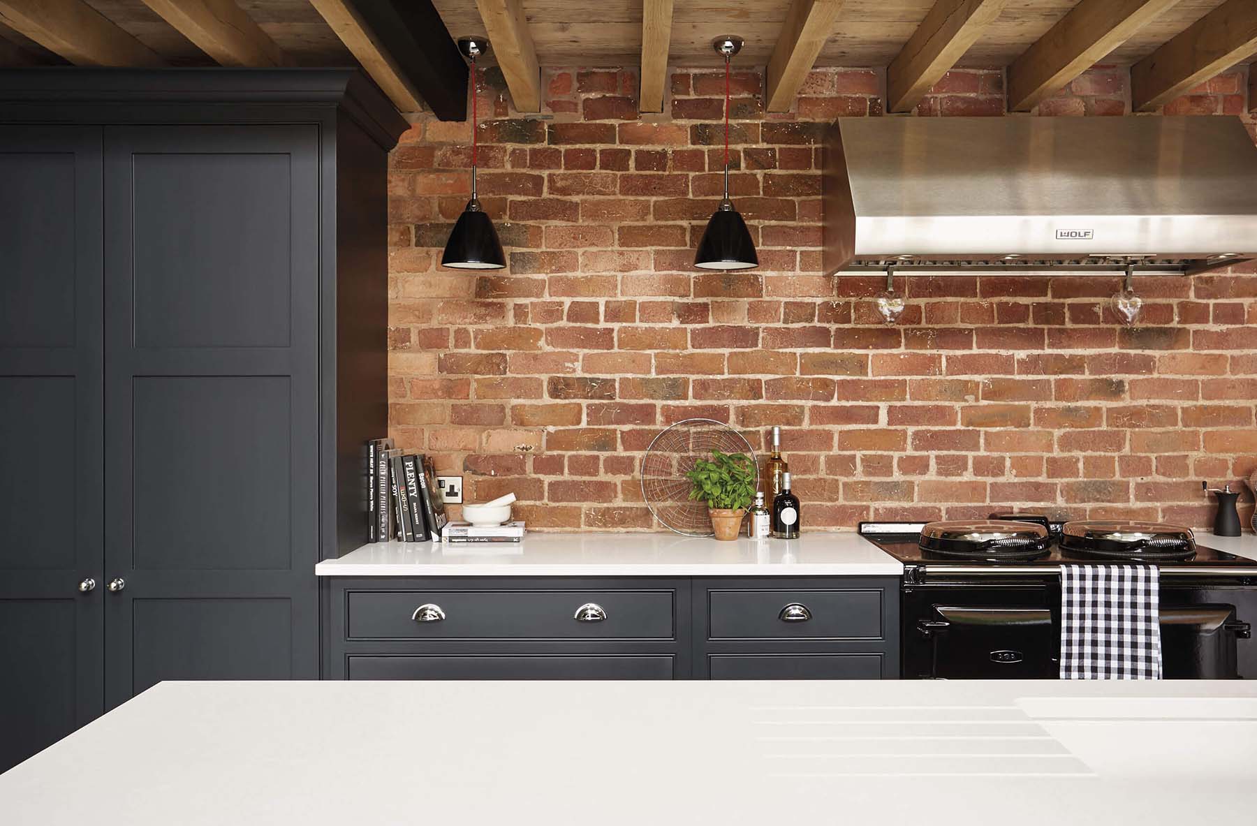 dark gray cabinets with white countertops exposed wood ceilings brick backsplash