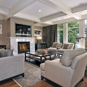 Beautiful living room with tan walls and white trim with marble fireplace surround and white coffered ceiling.